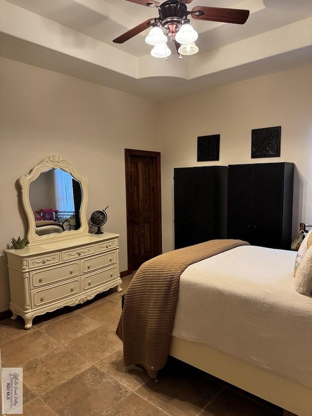 bedroom featuring a raised ceiling and ceiling fan