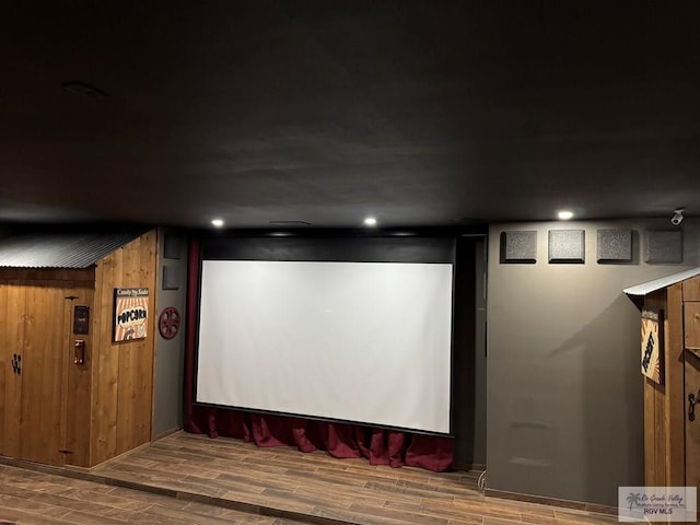 home theater room with hardwood / wood-style flooring and wood walls