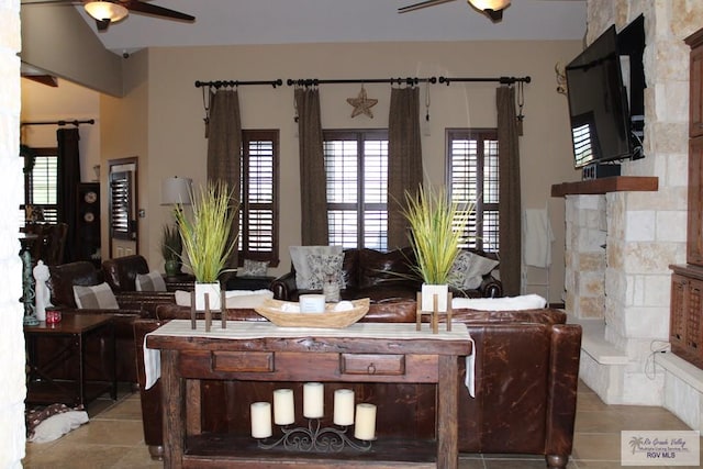 living room featuring ceiling fan, a fireplace, and light tile patterned floors