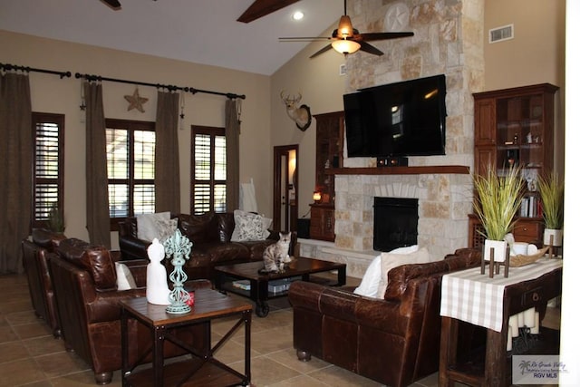 tiled living room with ceiling fan, a stone fireplace, and high vaulted ceiling