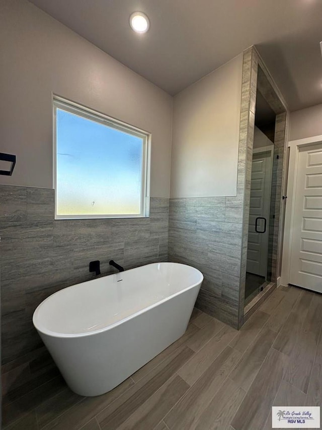 bathroom with shower with separate bathtub and tile walls