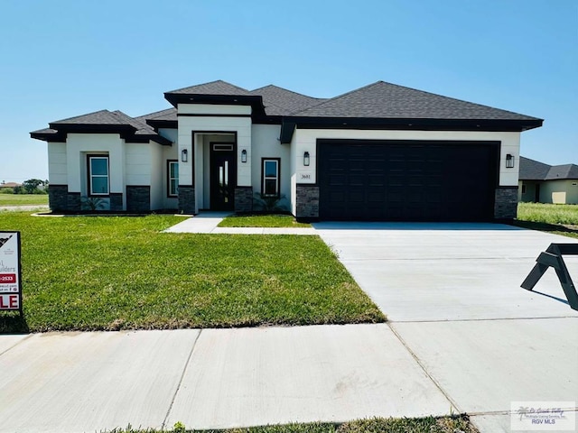 3601 Mattie Ln, Harlingen, TX 78550 - prairie-style home featuring stone siding, a garage, a front lawn, driveway, and a shingled roof