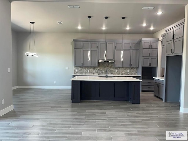 kitchen with gray cabinetry, sink, pendant lighting, and a center island with sink