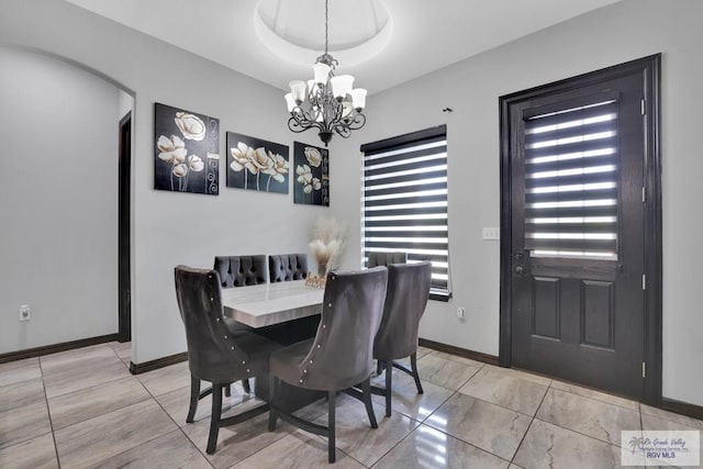 dining space featuring a tray ceiling, baseboards, and a notable chandelier