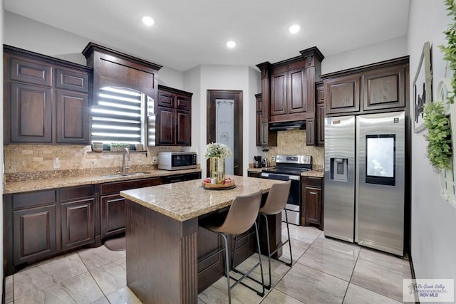 kitchen featuring dark brown cabinets, a sink, stainless steel appliances, and a center island