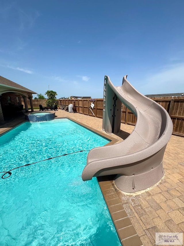 6020 Rusty Nail Dr, Brownsville, TX 78526 - view of pool with a water slide, a fenced backyard, and a pool with connected hot tub