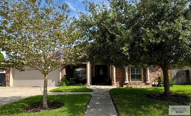 6020 Rusty Nail Dr, Brownsville, TX 78526 - view of property hidden behind natural elements featuring driveway, a front yard, brick siding, and a garage