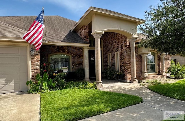 6020 Rusty Nail Dr, Brownsville, TX 78526 - view of front of home featuring a garage, a shingled roof, brick siding, and a front yard