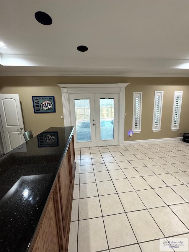 6020 Rusty Nail Dr, Brownsville, TX 78526 - kitchen featuring french doors, crown molding, light tile patterned flooring, brown cabinetry, and dark stone countertops