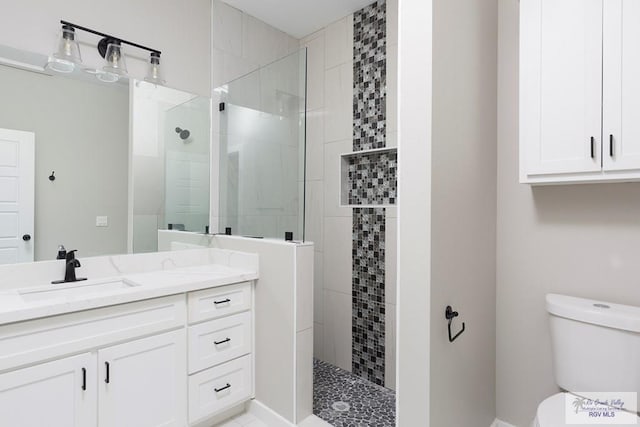 bathroom with tiled shower, vanity, and toilet