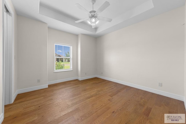 8005 King Sago Ct, Harlingen, TX 78552 - empty room featuring a raised ceiling, light wood-style flooring, and ceiling fan