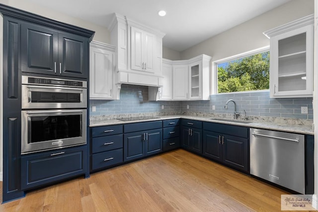 8005 King Sago Ct, Harlingen, TX 78552 - kitchen with appliances with stainless steel finishes, white cabinets, blue cabinetry, light wood finished floors, and glass insert cabinets