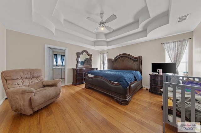 6540 Dockberry Rd, Brownsville, TX 78521 - bedroom featuring a raised ceiling, light wood-type flooring, connected bathroom, and a ceiling fan