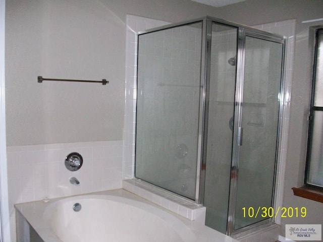 bathroom featuring shower with separate bathtub