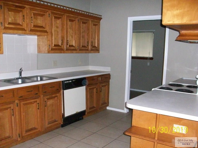 kitchen with backsplash, dishwasher, light tile patterned floors, and sink