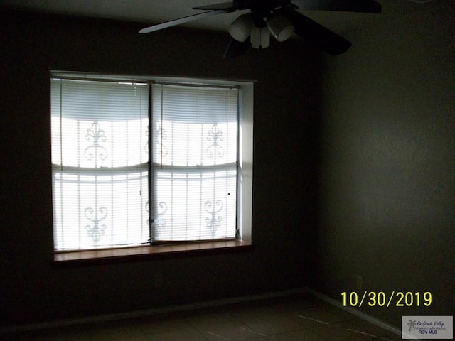 tiled empty room featuring ceiling fan