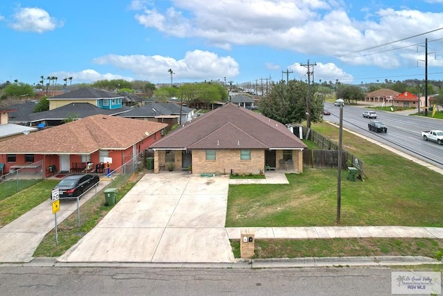 view of front of property featuring brick siding, a front yard, fence, a residential view, and driveway