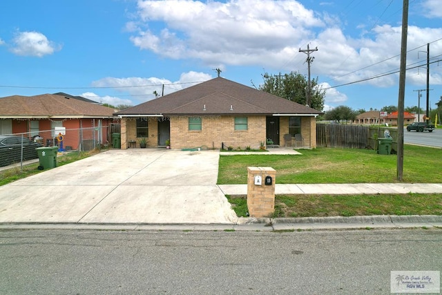 view of front of home with brick siding, a front yard, and fence