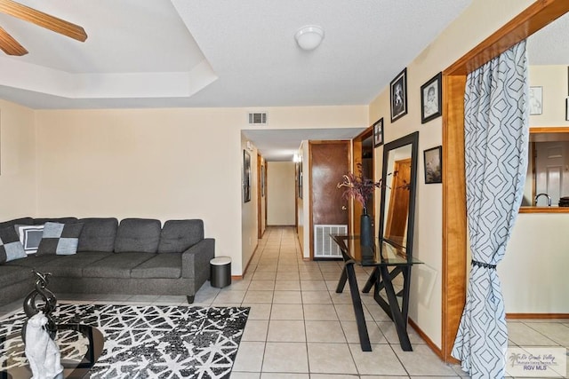 living area with light tile patterned floors, visible vents, baseboards, and ceiling fan