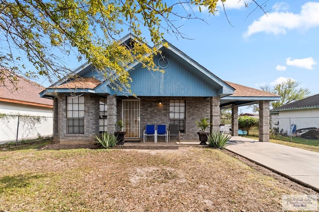 back of house featuring an attached carport, concrete driveway, a lawn, and fence