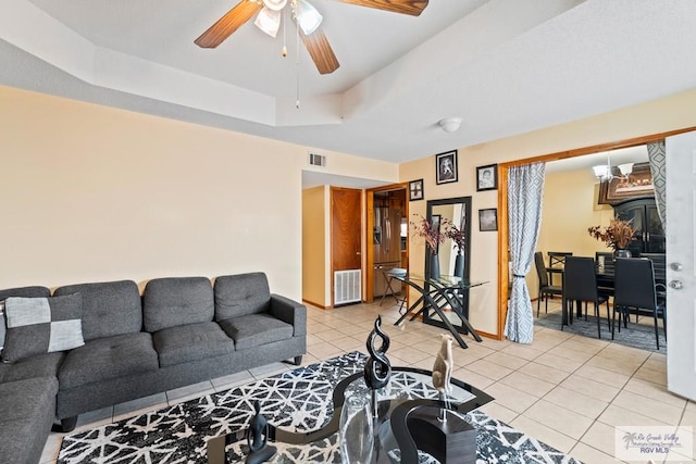 living area with visible vents, a raised ceiling, light tile patterned flooring, and a ceiling fan