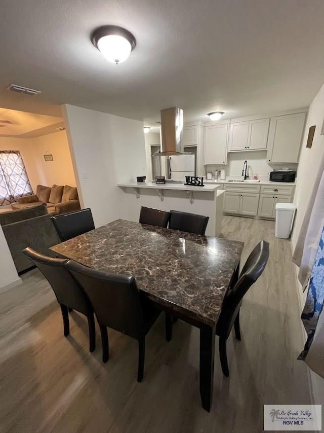 dining room featuring sink and light hardwood / wood-style flooring