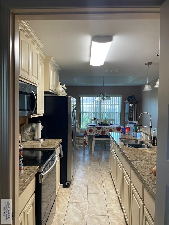 kitchen featuring cream cabinetry, sink, stainless steel appliances, and hanging light fixtures