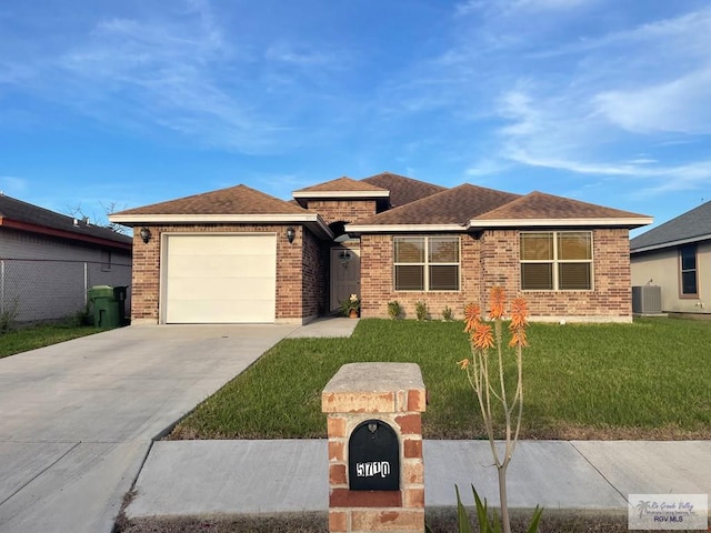 view of front of home featuring a front yard, a garage, and central air condition unit