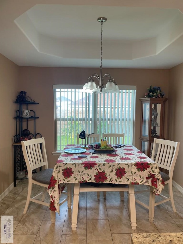 dining area featuring a raised ceiling and an inviting chandelier