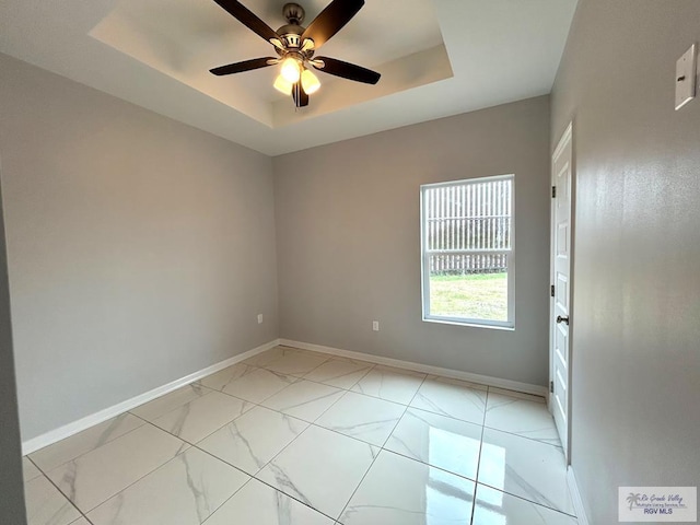 empty room with a tray ceiling and ceiling fan