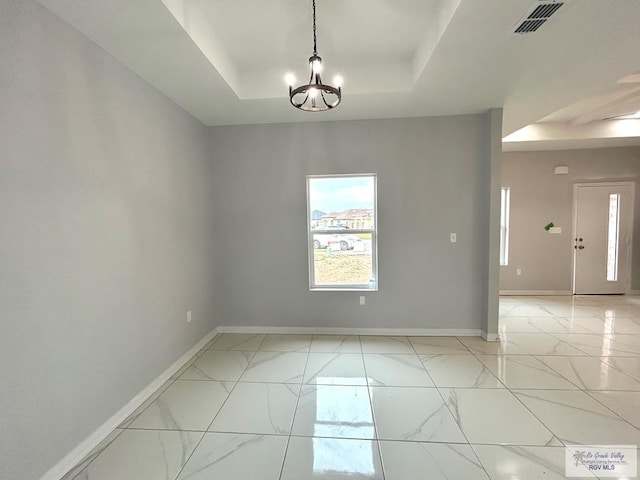 unfurnished room with a chandelier and a tray ceiling