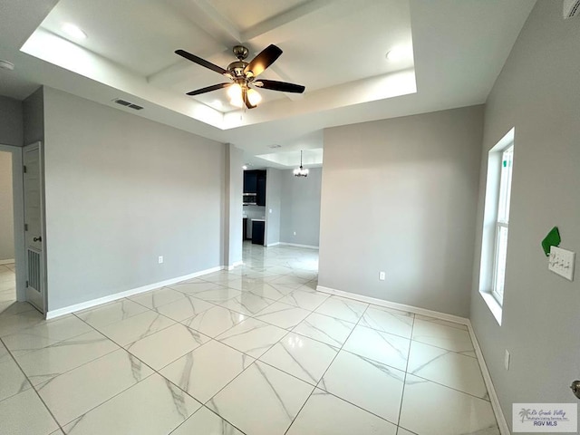 unfurnished room featuring ceiling fan and a tray ceiling