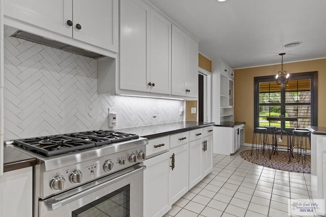 509 Lake Dr, Harlingen, TX 78550 - kitchen featuring stainless steel stove, dark countertops, tasteful backsplash, light tile patterned floors, and white cabinetry