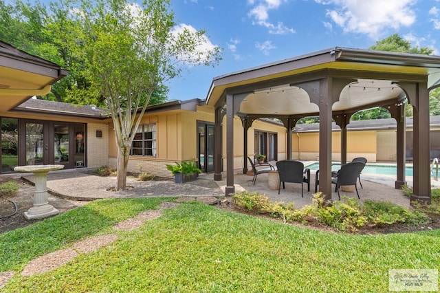 509 Lake Dr, Harlingen, TX 78550 - back of property featuring french doors, a patio, brick siding, an outdoor pool, and a lawn
