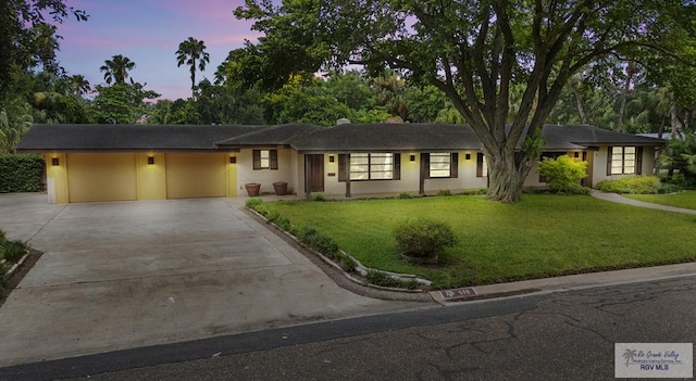 509 Lake Dr, Harlingen, TX 78550 - ranch-style house with driveway, an attached garage, a lawn, and stucco siding