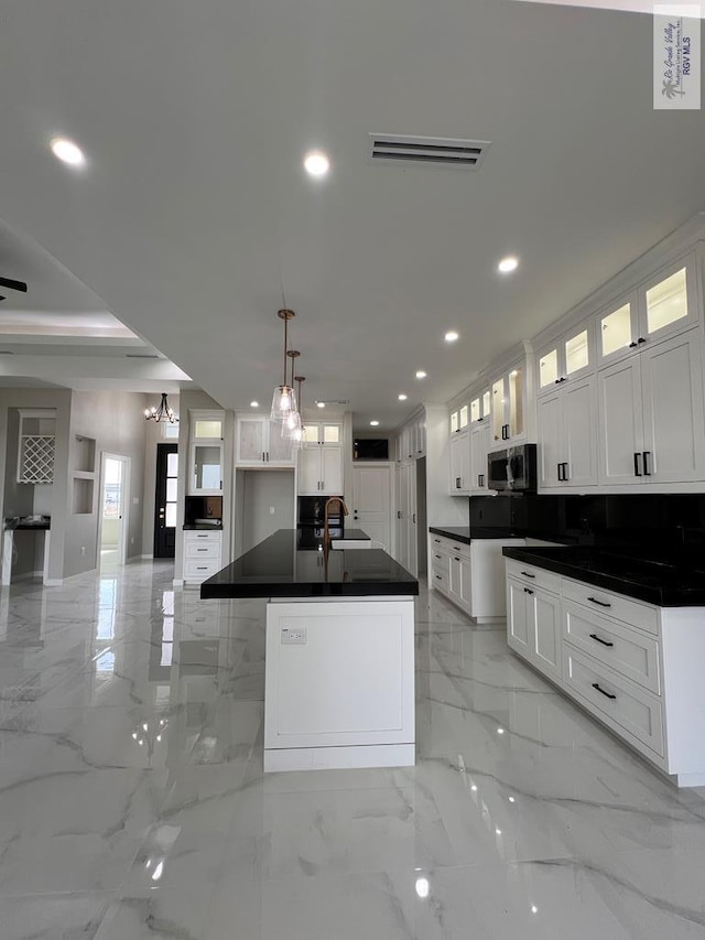 kitchen featuring dark countertops, stainless steel microwave, marble finish floor, a sink, and recessed lighting