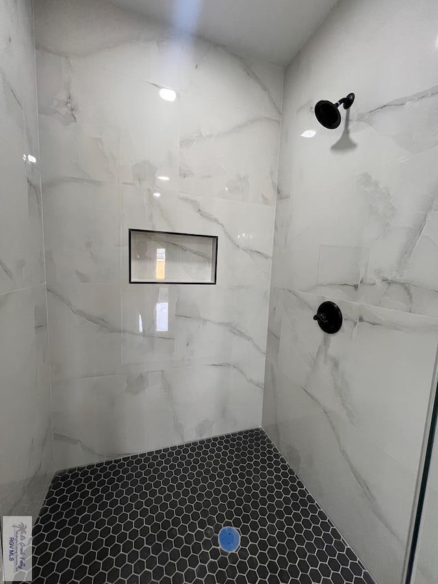 bathroom featuring a marble finish shower