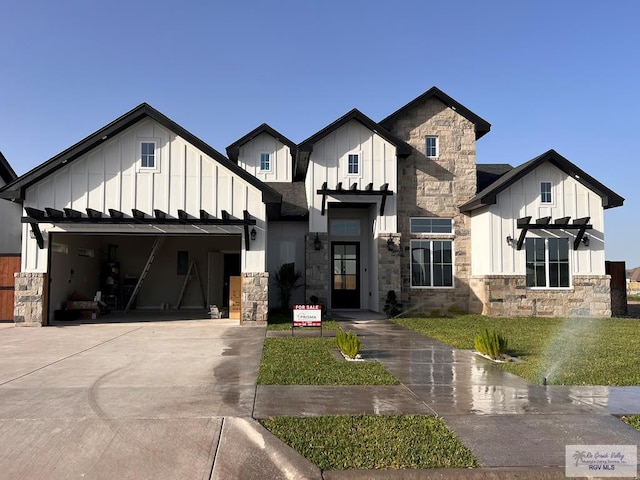 modern inspired farmhouse featuring an attached garage, driveway, stone siding, roof with shingles, and board and batten siding