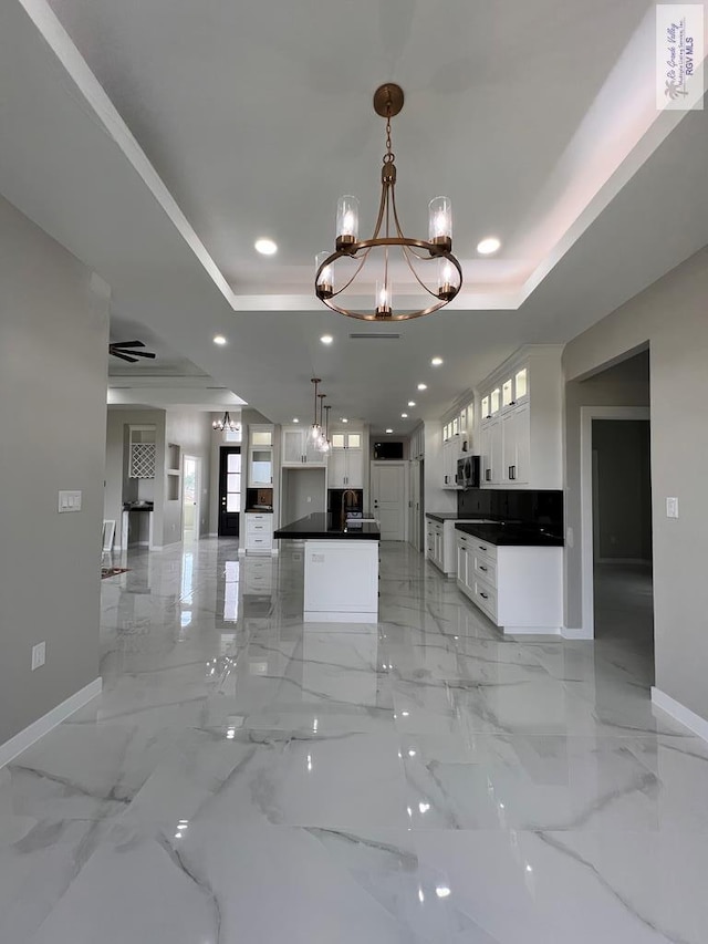 kitchen featuring white cabinets, an inviting chandelier, a raised ceiling, and recessed lighting