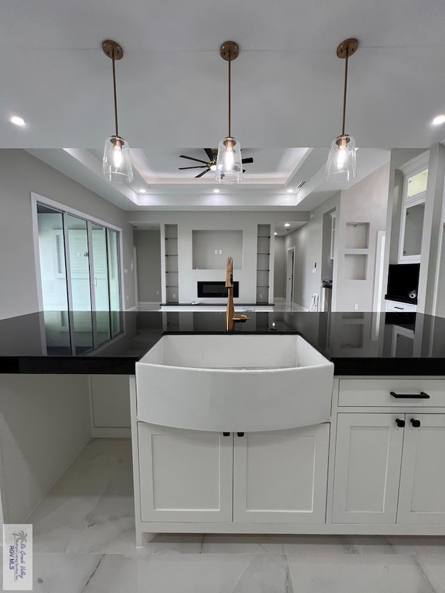 kitchen featuring a tray ceiling, marble finish floor, dark countertops, open floor plan, and white cabinets