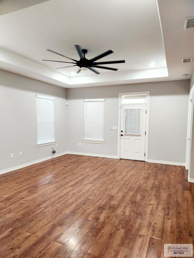 spare room with a raised ceiling, ceiling fan, and hardwood / wood-style flooring