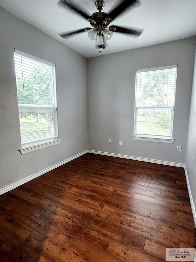 empty room with plenty of natural light, ceiling fan, and dark hardwood / wood-style flooring