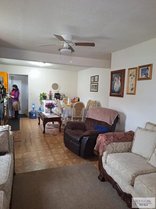 living room featuring ceiling fan, wood-type flooring, and a textured ceiling