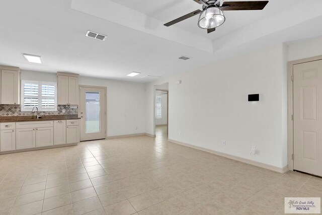 unfurnished living room with light tile patterned floors, ceiling fan, and sink