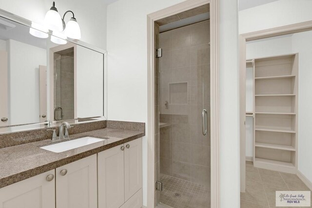 bathroom featuring tile patterned flooring, vanity, a chandelier, and an enclosed shower