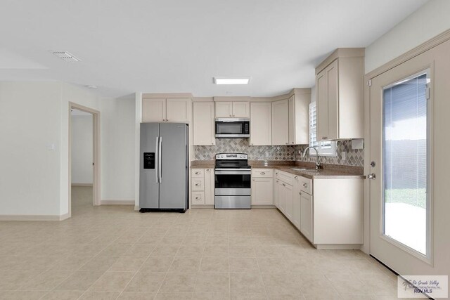 kitchen with light tile patterned floors, backsplash, stainless steel appliances, and sink