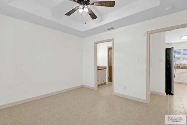 spare room with ceiling fan, a raised ceiling, light tile patterned floors, and sink