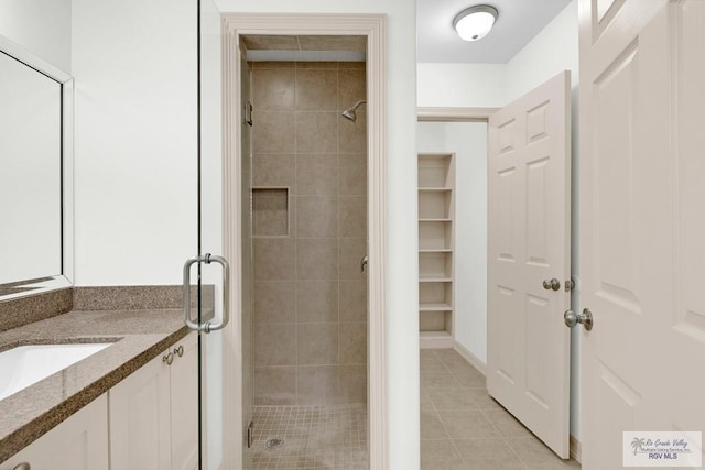 bathroom featuring tile patterned flooring, vanity, and a shower with door