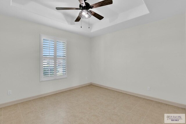 spare room featuring a raised ceiling and ceiling fan