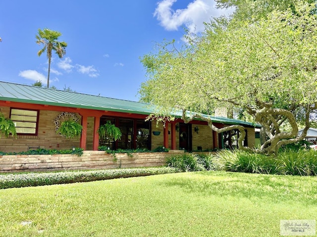 1914 S Parkwood Dr, Harlingen, TX 78550 - view of front facade with brick siding, a front lawn, a standing seam roof, and a metal roof